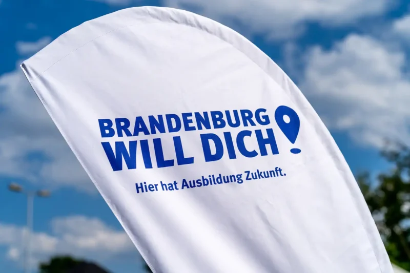 Werbefahne der Kampagne 'Brandenburg Will Dich' vor blauem Himmel; Referenz für Public Sector Branding von Stefan Schubert