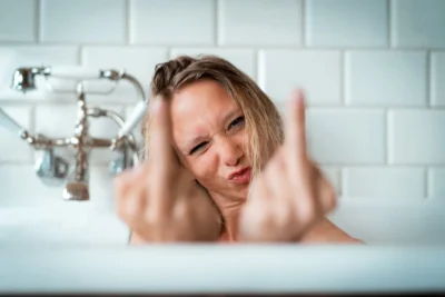 Provokante Inszenierung: Frau in Badewanne zeigt Mittelfinger; Charakter-Aufnahme von Stefan Schubert.