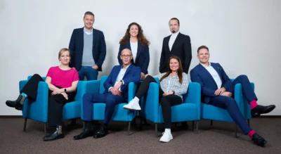 Moderne Team-Dynamik: Gruppenfoto in entspannter Atmosphäre durch Sitzposition Kleidung; Businessfotografie Stefan Schubert