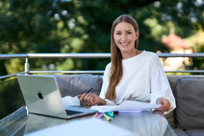 Corporate: Eine Unternehmerin arbeitet mit Laptop auf ihrem Balkon im Grünen, Stefan Schubert Fotografie Berlin.