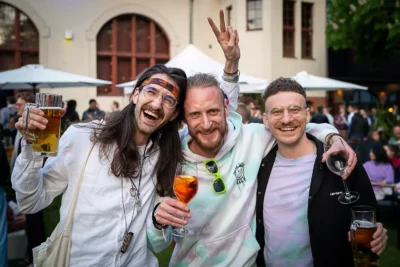 Authentische Eventfotografie: Lachende Mitarbeiter mit Getränken bei einer Firmenfeier; Foto von Stefan Schubert Fotografie