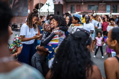 Teilnehmer umarmen sich freudig-strahlend beim African Food Festival in der Malzfabrik Berlin; Eventfotograf Stefan Schubert