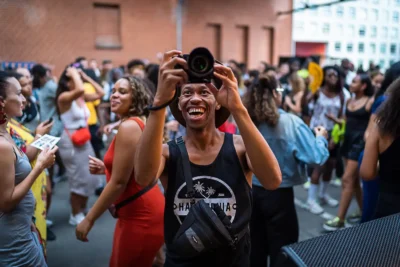 Lebendige Festivalfotografie: Gast fotografiert lachend inmitten einer tanzenden Menge; Eventfotografie von Stefan Schubert