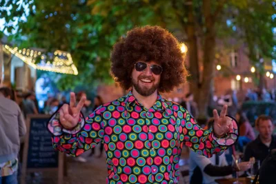 Lustiges Corporate-Event Foto: Gast mit Hippie-Perücke im Retro-Outfit auf Firmenfeier; von Stefan Schubert Fotografie