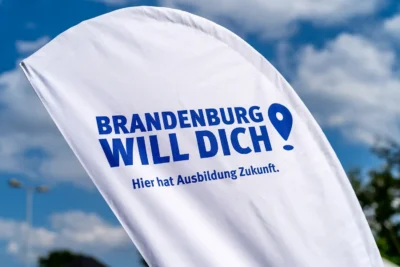 Werbefahne der Kampagne 'Brandenburg Will Dich' vor blauem Himmel; Referenz für Public Sector Branding von Stefan Schubert
