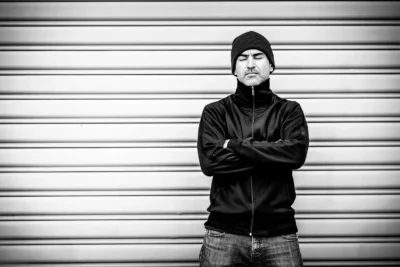 Künstlerportrait in S/W; Coverart eines Musikers im urbanen Berlin vor Rolltor – von Stefan Schubert Fotografie