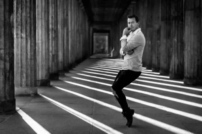 Künstlerporträt: Mann in Tanzpose im Säulengang; Licht-Schatten-Spiel; Sedcard & Charakterfotografie von Stefan Schubert