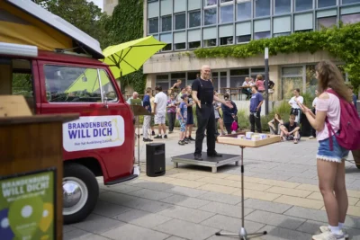 Roadshow-Event "Brandenburg Will Dich": Performance Künstler vor Jugendlichen am Kampagnen-Bus; Foto von Stefan Schubert