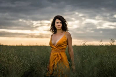 Schauspieler-Portrait: Frau im gelben Kleid im Feld bei Abendlicht; Outdoor-Charakterporträt von Fotograf Stefan Schubert.